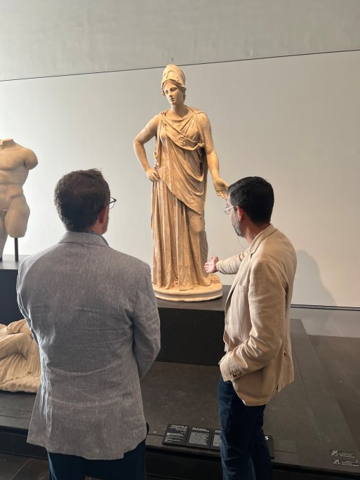 Une statue en bronze d'une personne, des portraits et d'autres artefacts exposés au Louvre Abu Dhabi.